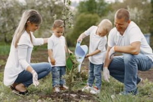 Famiglia con due bambini che annaffia un albero appena piantato
