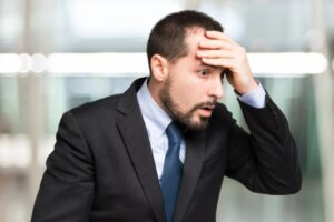 uomo preoccupato con una mano sulla fronte
