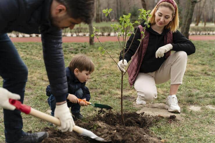 Bimbo e genitori che piantano un albero