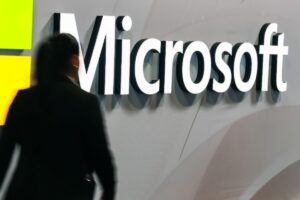 Donna che passa vicino allo stand Microsoft in una fiera di tecnologia