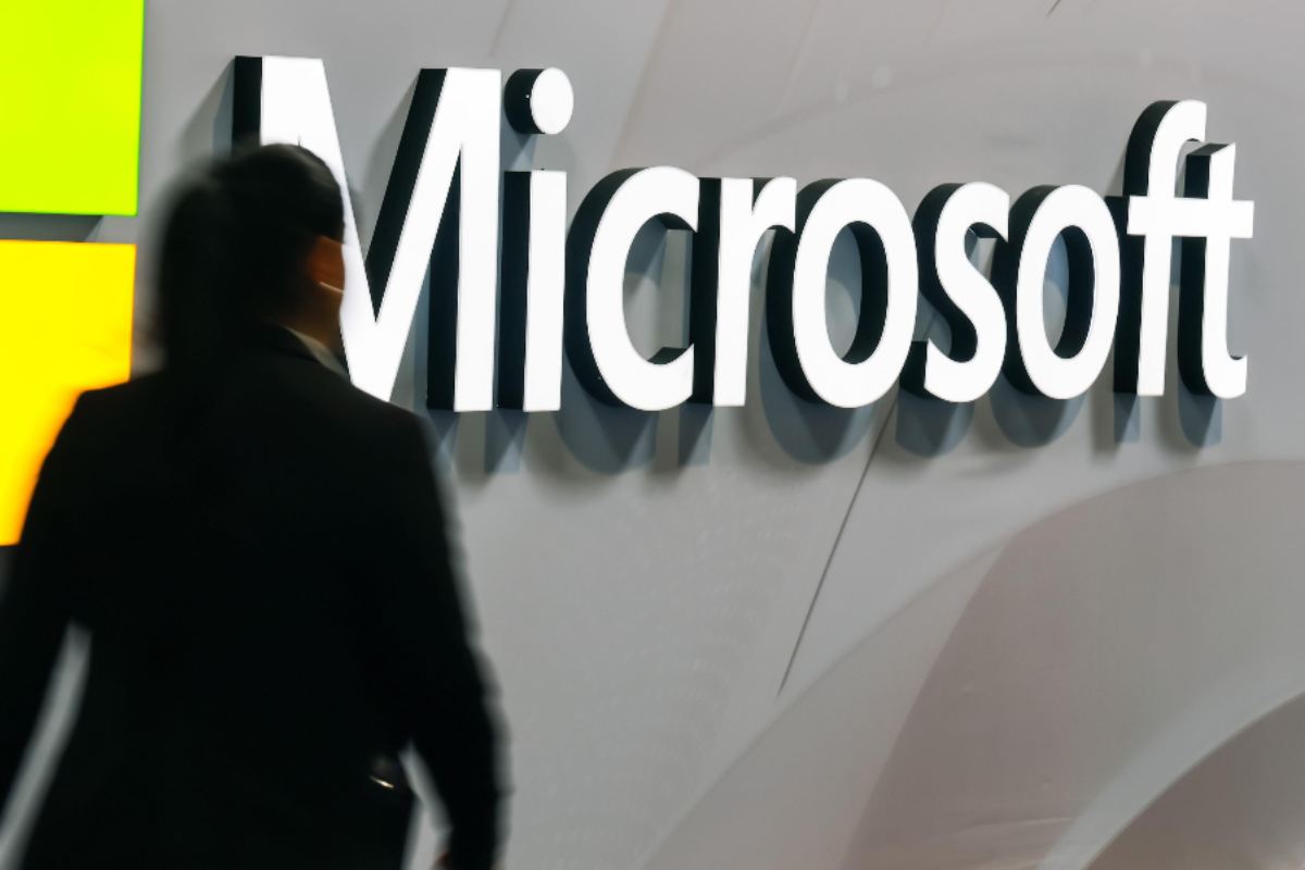 Donna che passa vicino allo stand Microsoft in una fiera di tecnologia
